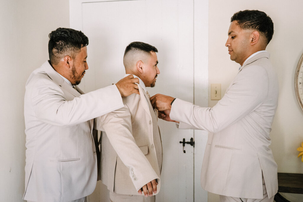 Groomsmen helping groom get ready on wedding day